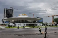 Un edificio con forma de "plato volador" en el centro de Biskek. En el tejado se lee "Circo" en letras grandes. Al fondo se ven tres grúas de obra y un rascacielos en construcción.