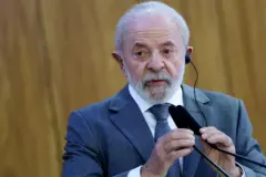 Lula olhando compenetrado para algo, usando fone para tradução e mexendo em microfone