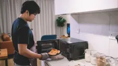 رجل يُخرج شريحة بيتزا من الميكروويف.