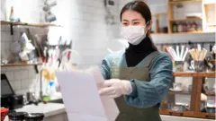 asina small business owner with face mask in coffee shop