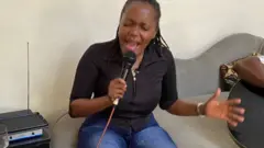 Jane Uwimana arimo gukora imyitozo yo kuririmba