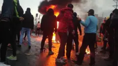 Iranian protesters gather around a fire during a demonstration against an increase in gasoline prices in the capital Tehran, on November 16, 2019