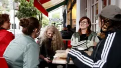 People sit at a restaurant in inner-city Sydney on the first day of the city's reopening