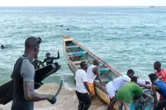 Des secouristes sénégalais et des pêcheurs locaux préparent une pirogue.