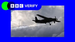 一架小型飛機的剪影可見於空中，正向天空噴灑細小顆粒，並在其後方形成一道長長的白色軌跡；飛機在厚重的灰色雲層背景下飛行。左上角可見BBC事實核查（BBC Verify）的標誌