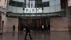 د بي‌بي‌سي کار کوونکي په لندن کې د دغې شبکې مرکزي دفتر ته د ننوتو په حال کې. 
