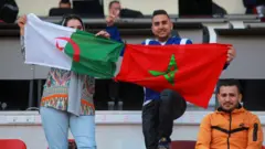 مغربي وجزائرية يرفعان علمي البلدين جنبا إلى جنب في إحدى بطولات كرة القدم