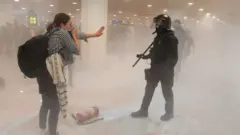 Una mujer le habla a un policía en El Prat