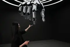 Una mujer toca una mano robótica durante una gira de prensa por el centro de exposiciones Robot World en Pekín el 17 de abril de 2025.
