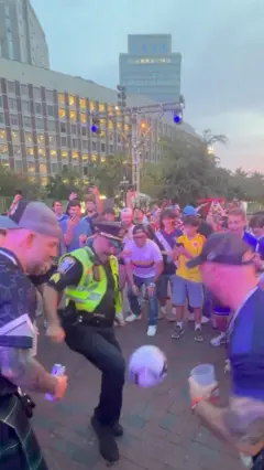 Policier qui jongle dans une foule supporters