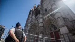 A police officer stares up at the charred front of the cathedral in Nantes