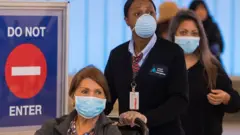 People wear face masks after arriving at the LAX airport in Los Angeles on 5 March 2020
