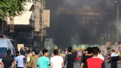 Masu zanga-zanga a Iraqi na kallon hayakin da ya turnike bayan taho mu gama tsakaninsu da jami'an tsaro da ke neman kora su a watan Nuwamba