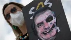 A woman holds a poster with an image representing the President of Brazil, Jair Bolsonaro, painted as a skull, during a demonstration rejecting the handling of the pandemic by his Government, in Brasilia, Brazil, 20 October 2021.