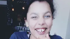 Giorgia Green sorrindo para foto dentro de casa
