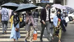 ጫንጥላ የያዙ ሰዎች በአዲስ አበባ ጎዳና