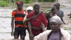 Man carrying a woman in a flood