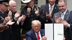 Трамп демонстрирует подписанный указ о реформе полиции