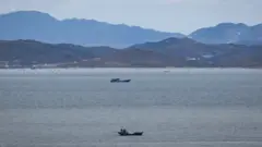 Unidentified fishing boats before the North Korean coastline from a viewpoint on the South Korea-controlled island of Yeonpyeong near the disputed waters of the Yellow Sea at dawn.
