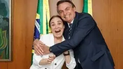 Jair Bolsonaro abraça Regina Duarte em gabinete com bandeiras do Brasil ao fundo