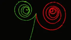 La producción simétrica de la materia y antimateria. Dos fotones invisibles de rayos gamma entran y cada uno produce un electrón (verde) y un positrón o antielectrón (rojo).