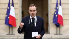Sébastien Lecornu, Olootu ijọba ilẹ France to fipo silẹ lẹyin ọjọ 26.. Ọkunrin naa n ṣalaye ọrọ lọwọ ninu aworan yii, o wọṣọ dudu to ni itẹnu funfun, iwe kan wa lọwọ rẹ, bẹẹ ni ẹrọ gbohun-gbohun meji wa niwaju rẹ pẹlu. Awọn asia meji lẹgbẹ ọtun ati osi ko gbẹyin.