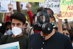 दिल्लीस्थित इन्डिया गेटनजिकै मास्क लगाएर वायु प्रदूषण नियन्त्रण गर्न माग गर्दै उभिएका युवाहरू