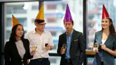 four office persons wearing party hats