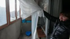 Une femme montrant sa fenêtre éclatée.