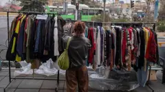زنی در حال انتخاب لباس در کنار خیابانی در تهران