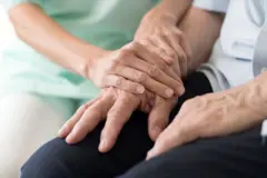 يد شابة تمسك بيد مسنّ مريض