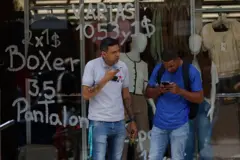 Personas frente a una tienda que exhibe precios en bolívares (moneda oficial venezolana) y dólares estadounidenses en Caracas, Venezuela, el 2 de junio de 2025.