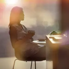 Mulher sentada tomando uma xícara de café ao sol