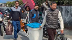 प्रतिनिधिसभा सदस्य निर्वाचनका लागि मतदान सामग्री बुझेर मतदान केन्द्रतर्फ लिएर जाँदै मतदानमा खटिएका कर्मचारी