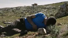 Bazel Adre sa kamerom na Zapadnoj obali dok se iza njega vidi vojni buldožer 