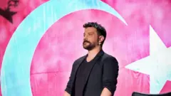 Oğuzhan Uğur, Türk bayrağının önünde ayakta duruyor