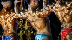 Três fisiculturistas de costas fazem exercícios para ganhar músculos