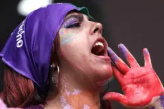 Mor bir bandana takmış bir kadın slogan atarken. 