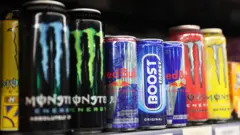 Close of of differnet energy drink brands lined up on a shelf in a supermarket