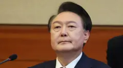 ダークスーツ姿の尹氏がマイクを前に前方を見ている