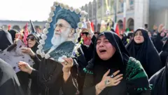 Mujer llora mientras otra exhibe una foto de Jamenei.