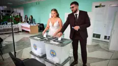 Жених и невеста голосуют на избирательном участке в селе Хорешты