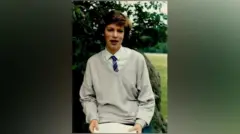 Katie Mitchell jovem, em uniforme escolar