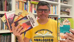 O escritor Marcelo Duarte segura livros da série Vaga-Lume