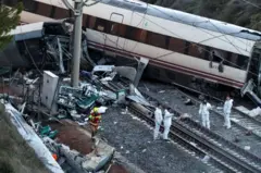 Vagones de tren yacen sobre la vía férrea tras el accidente en España, mientras investigadores examinan los escombros