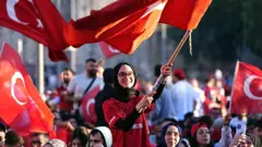 Meydanda topluca maçı izlerken bayrak sallayan bir kadın