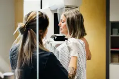 Mamogrfi yaptıran bir kadın, ona yardımcı olan bir kadın doktor