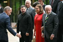 Lula se preparando para tirar foto. Ao lado dele está Janja, que está ao lado do presidente da Ucrânia Volodymyr Zelensky.