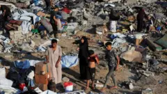 تعدادی از فلسطینی‌ها در میان بقایای محل حمله هوایی اسرائیل به یک خانه در غزه