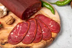 bir tahta üzerine sıralanmış dilim pastırmalar ve yeşil biber, sarımsak ve kabuklu ceviz